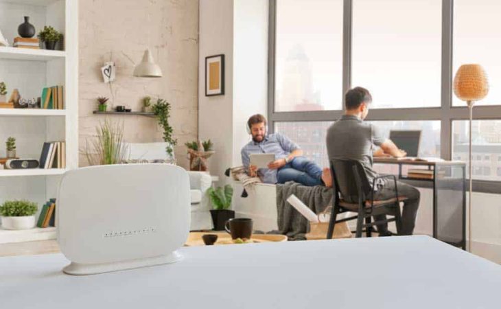 Router interior room on the table and two man is accessing WiFi.